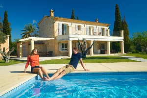 couple sitting on edge of pool with feet in the water smiling at each other